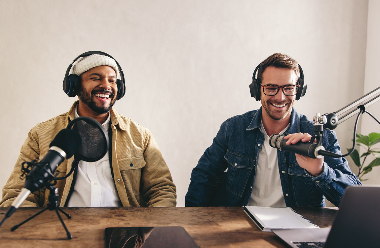 Two podcast hosts recording at microphones